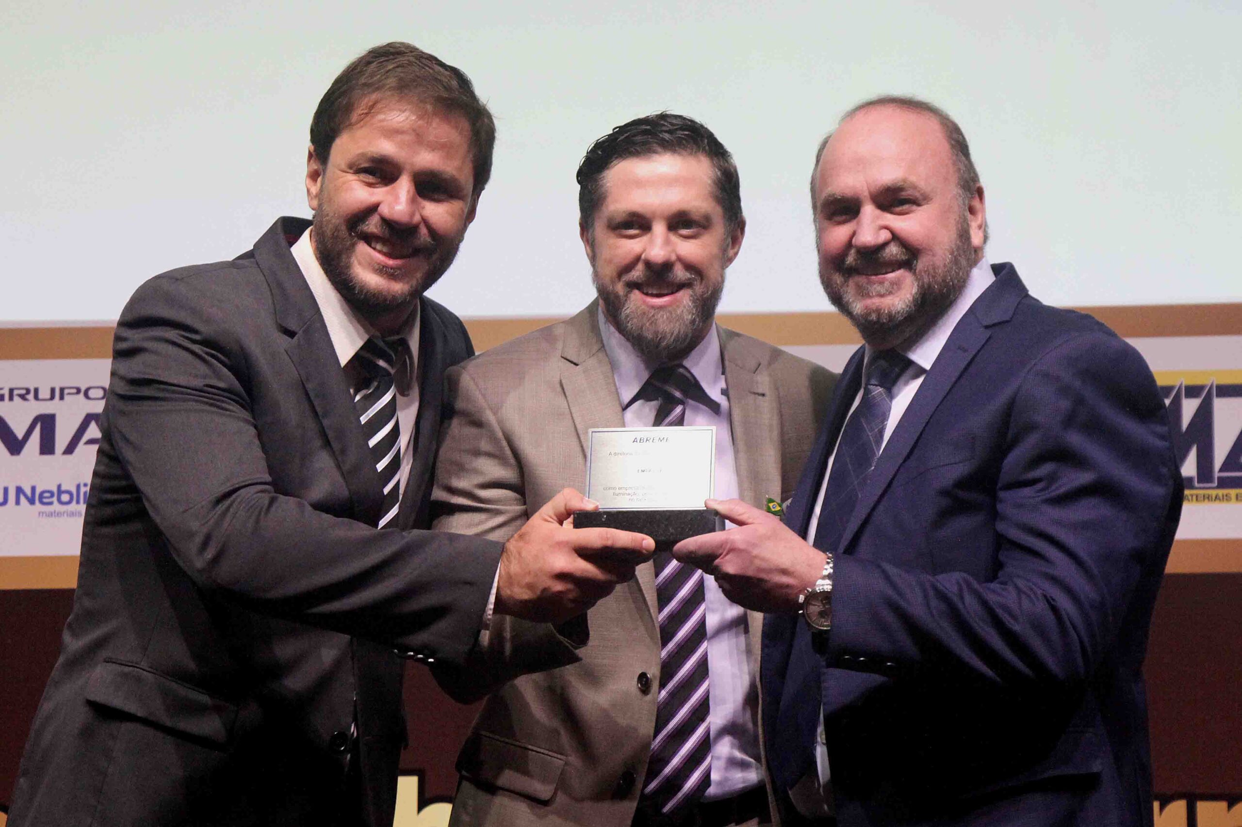 Diretor ABREME Sr. Paulo Henrique Durci entrega a placa destaque ranking 2024 no segmento Iluminação para empresa vencedora EMPALUX aos Srs. Bruno Rossi Diretor Comex e Supply Chain e Sr. Arno Grahl Diretor comercial.