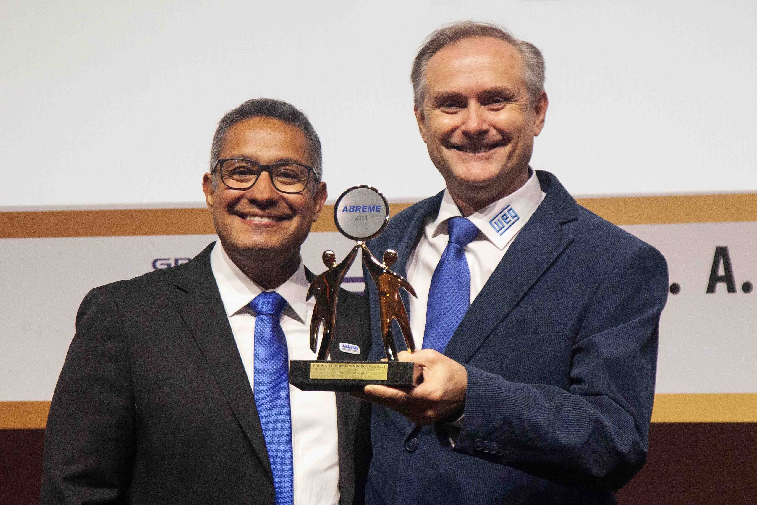 Diretor Sr. Thiago Espinheira entrega a Sr. Paulo Roberto Krüger Diretor Comercial da empresa WEG troféu Ouro 2024 segmento Dispositivos Elétricos Industriais .