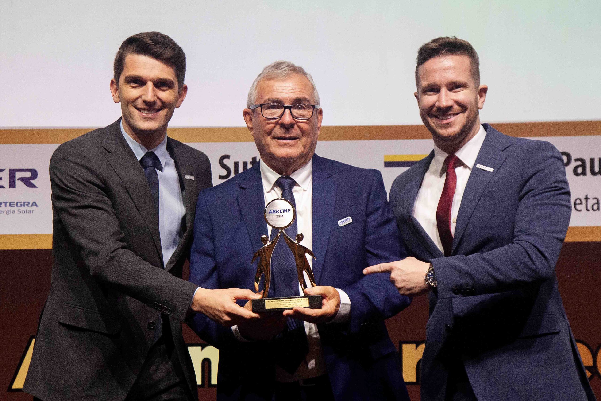 Diretor ABREME Sr. Reinaldo Gavioli entrega aos Srs. Lucas Zarpelon e Matheus Guerra Coordenadores de vendas da empresa Tramontina Elektric troféu Ouro 2024 segmento Infraestrutura.